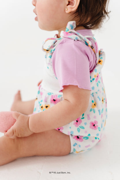 Baby wearing a colorful floral PEEPS® romper with a lavender undershirt on a white background