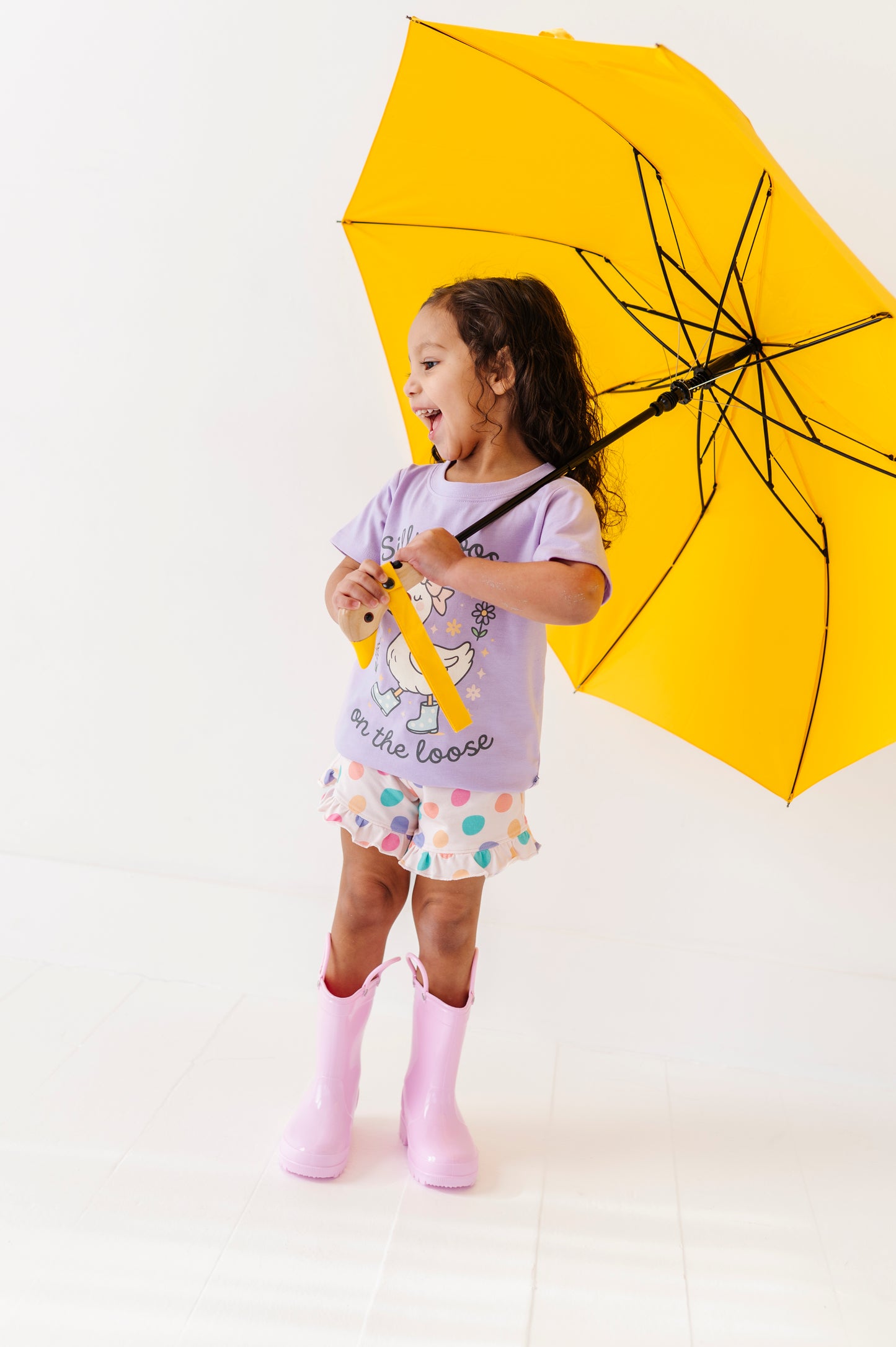 Child holding a yellow umbrella on a white background