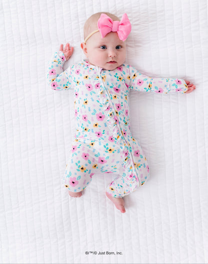 Baby in a floral PEEPS® romper with a pink bow on a white textured surface