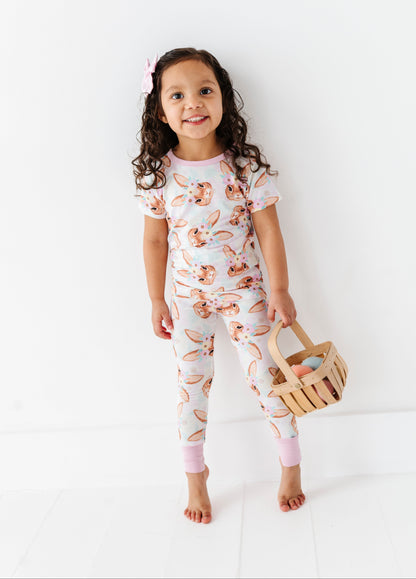 Child wearing a floral bamboo onesie holding a wooden basket on a white background
