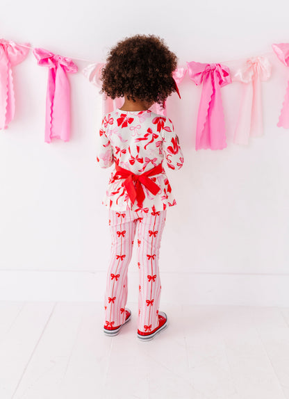 Back view of Blushing Bows peplum top showing statement red bow detail
