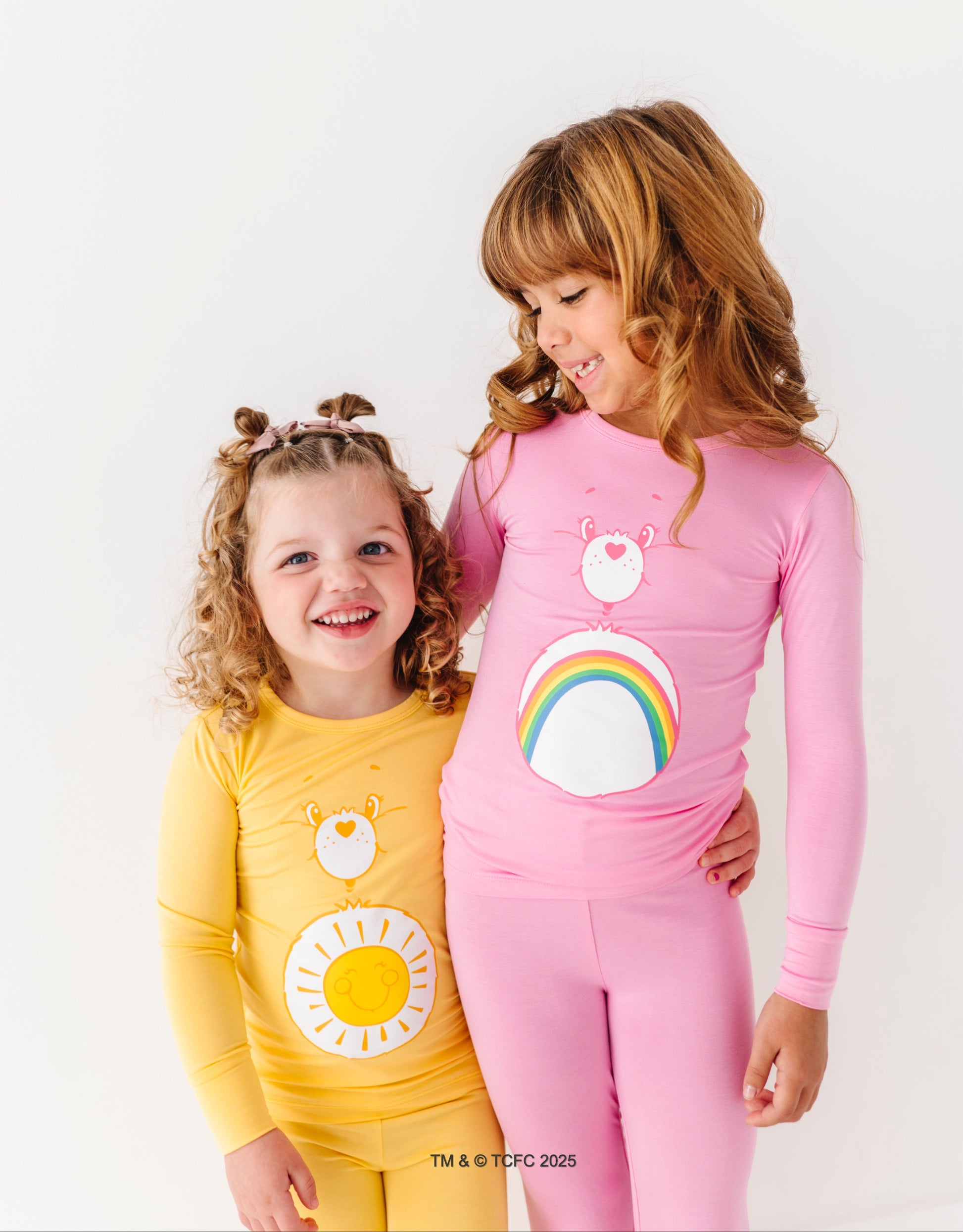 Kid smiling in Funshine Bear Care Bears pajamas on white background