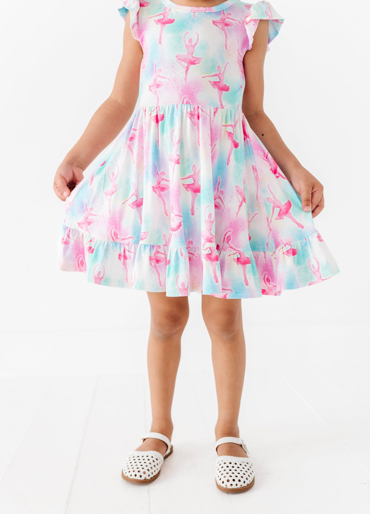 Child wearing a colorful bamboo dress with a ballet pattern on a white background