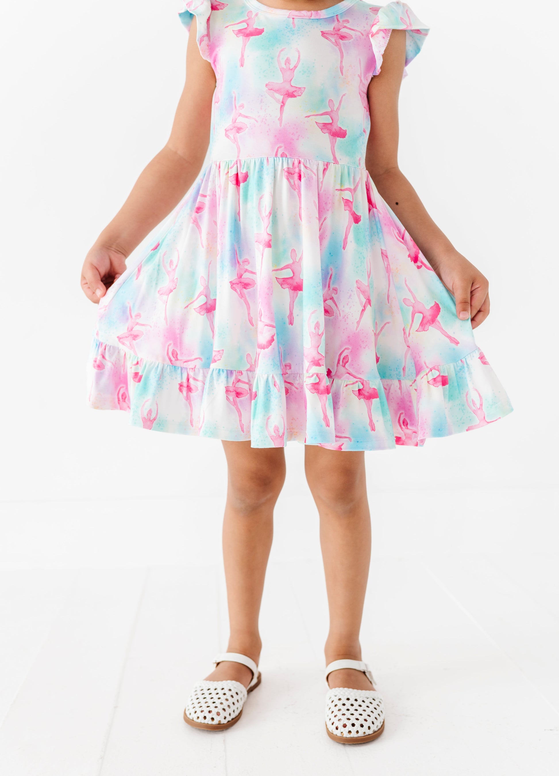 Child wearing a colorful bamboo dress with a ballet pattern on a white background
