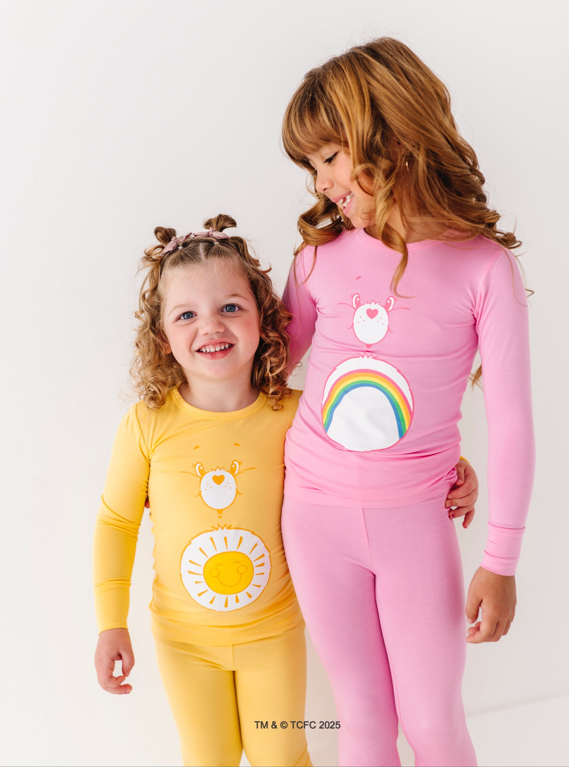 Child wearing Care Bears Cheer Bear pink bamboo pajamas with rainbow belly badge