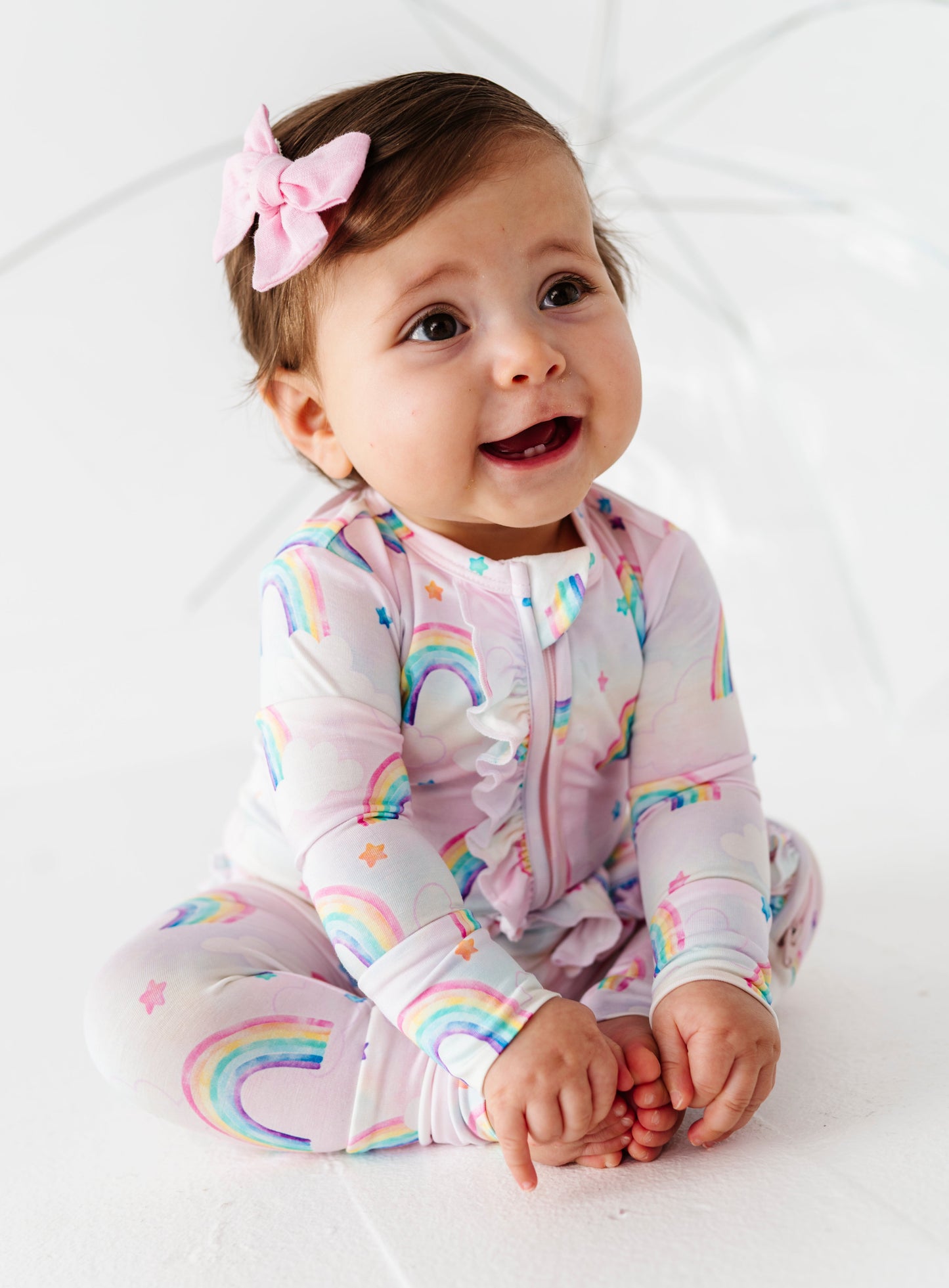 Baby wearing a rainbow-themed bamboo zip romper on a white background