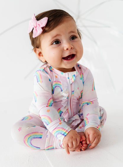 Baby wearing a rainbow-themed bamboo zip romper on a white background