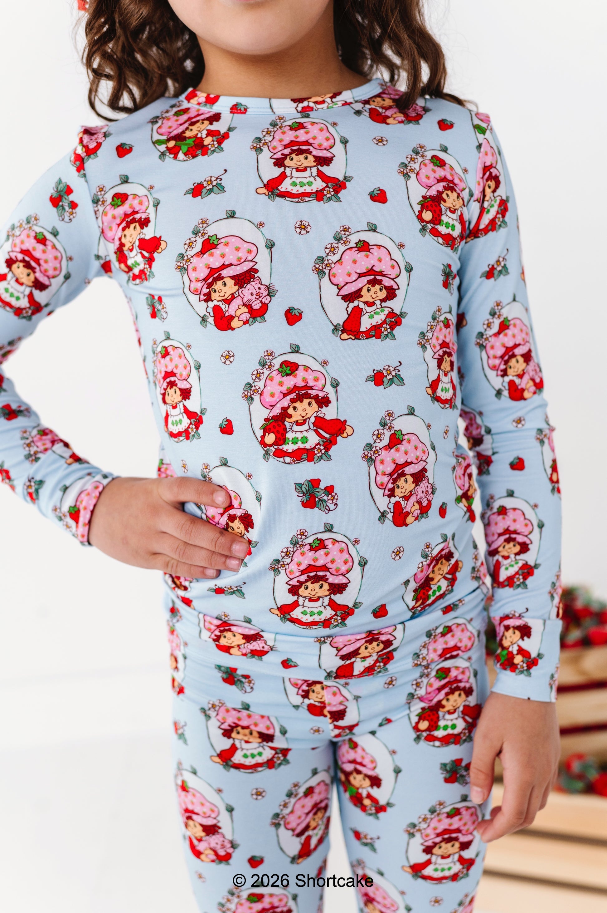 Children's pajama set with Strawberry Shortcake™ pattern on a light blue background