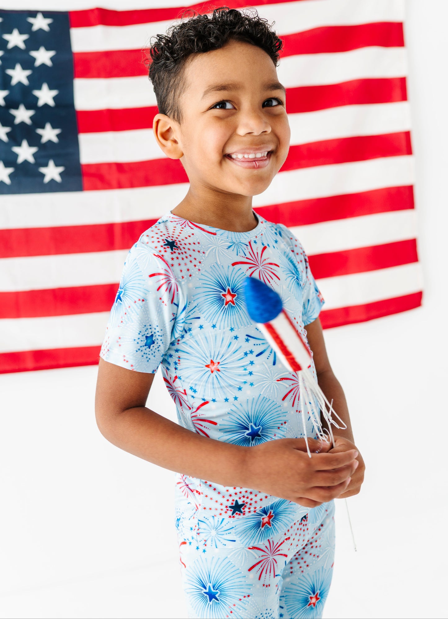 Child wearing a patriotic-themed bamboo pajama set with an American flag in the background