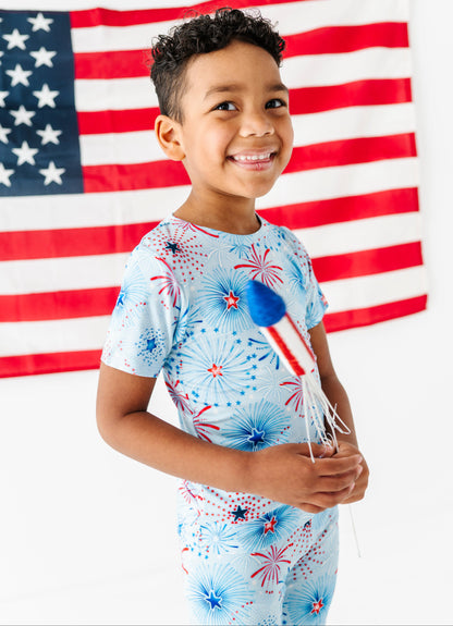 Child wearing a patriotic-themed bamboo pajama set with an American flag in the background