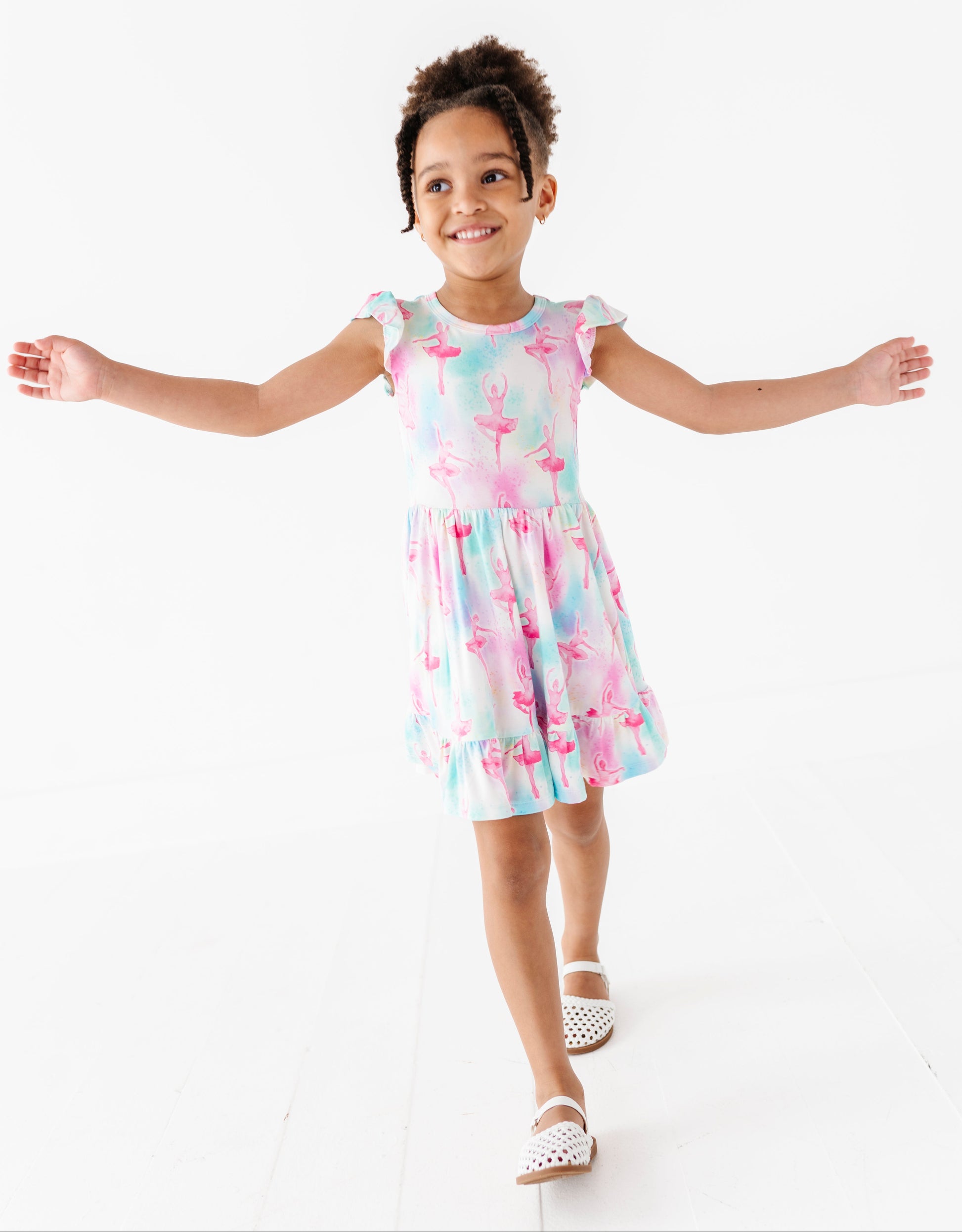 Young girl wearing a bamboo dress with a watercolor ballet pattern on a white background