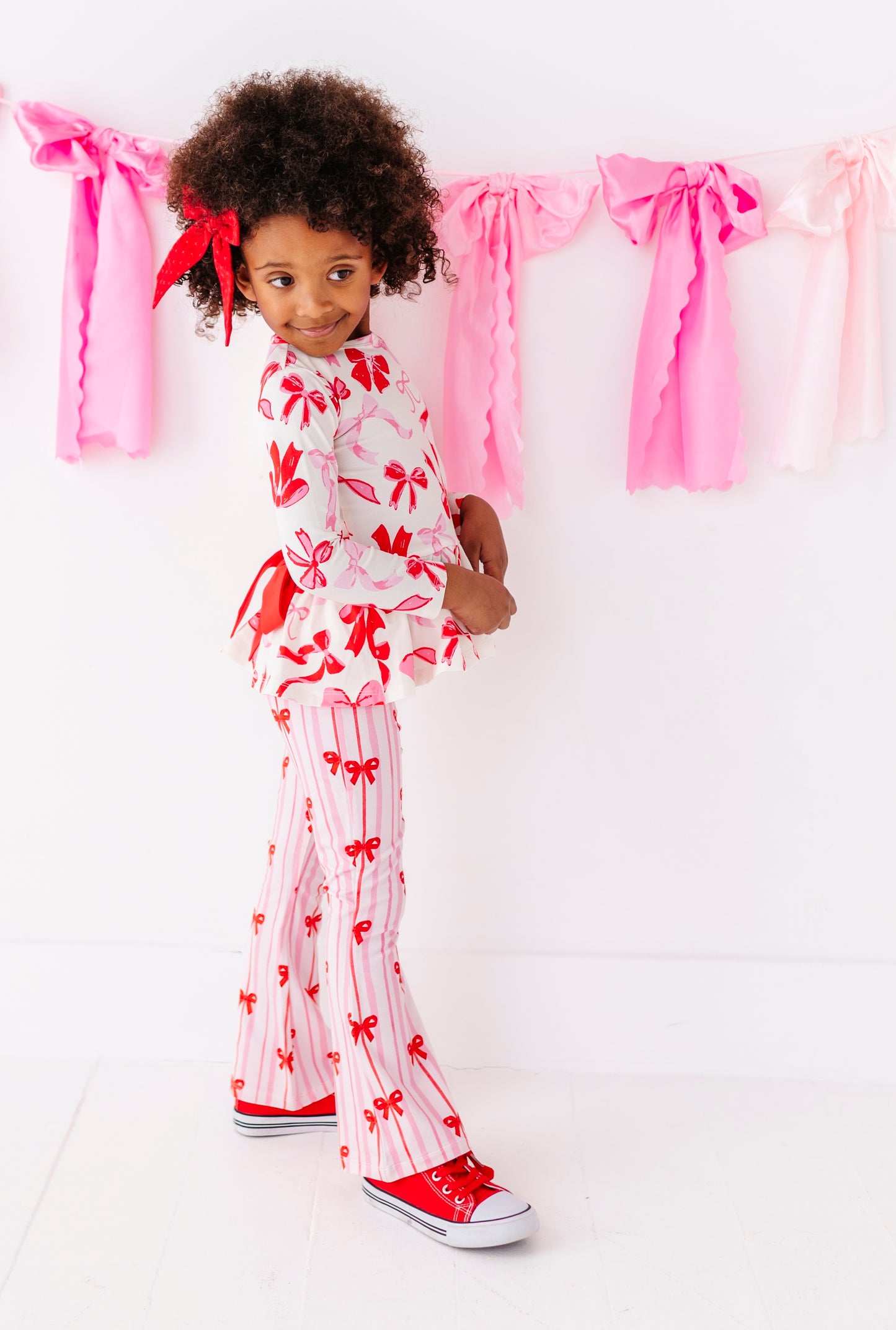 Toddler girl wearing festive Valentine’s ribbon print pants