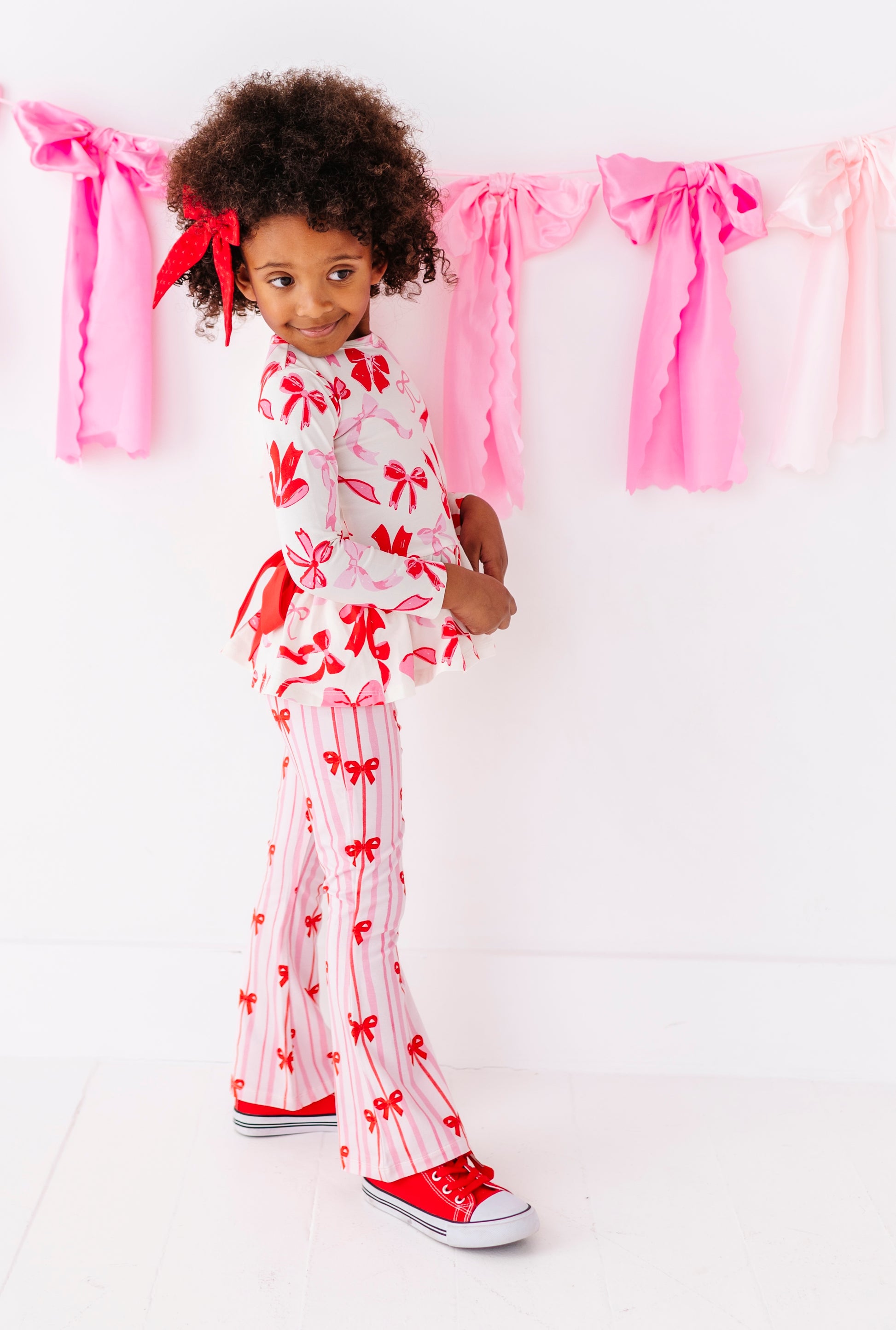 Toddler girl wearing festive Valentine’s ribbon print pants