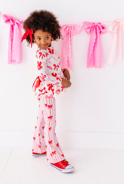 Toddler girl wearing festive Valentine’s ribbon print pants