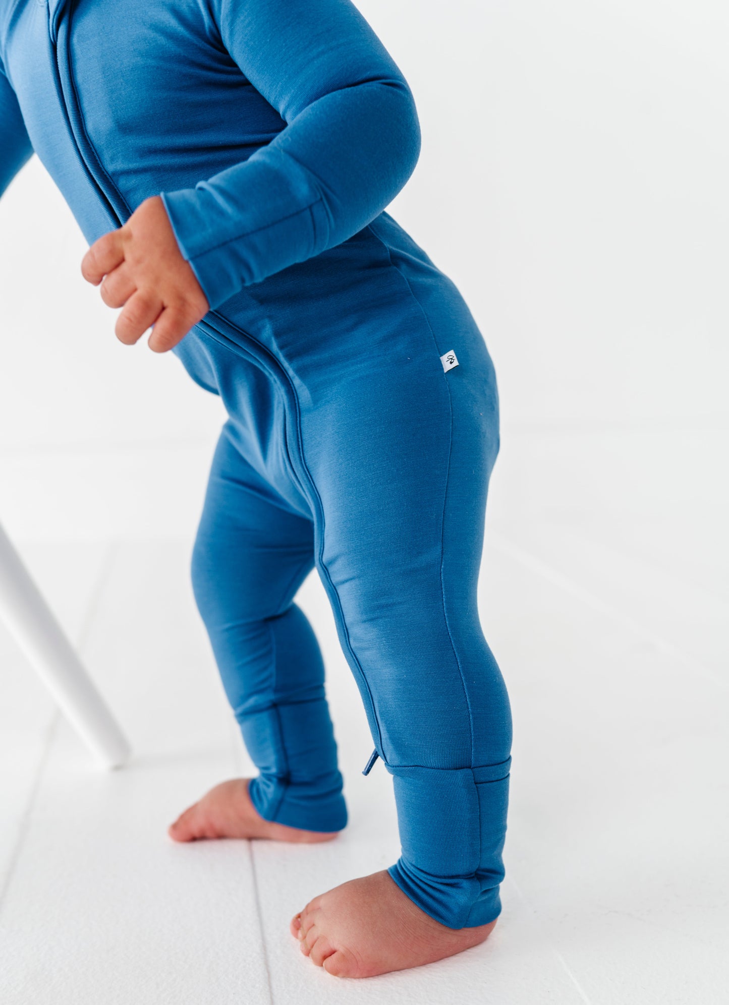 Child wearing blue bamboo zip romper on a white background