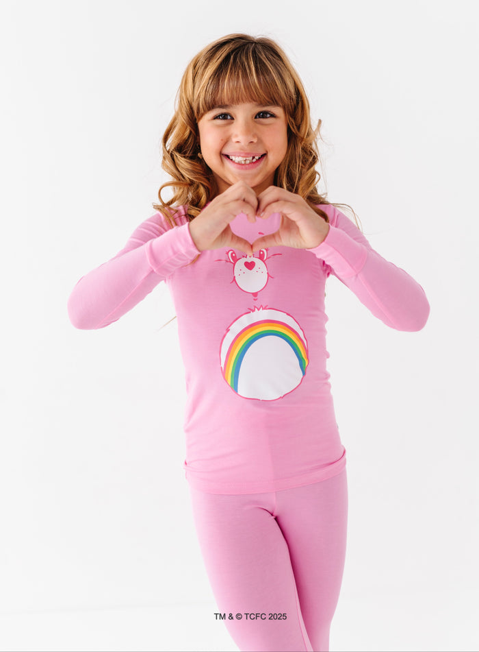 Child wearing Care Bears Cheer Bear pink bamboo pajamas with rainbow belly badge