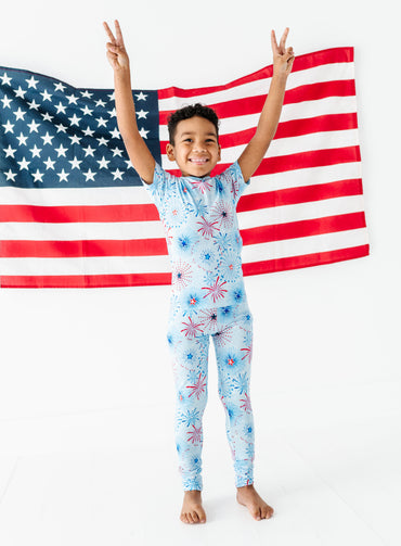 Young boy in bamboo firework pajamas with American flag in the background