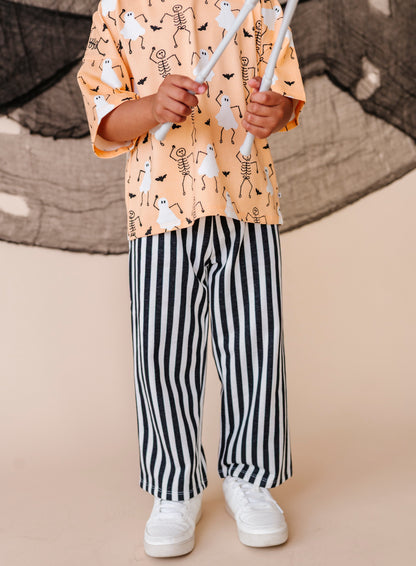 Child wearing a patterned shirt and striped pants on a beige background