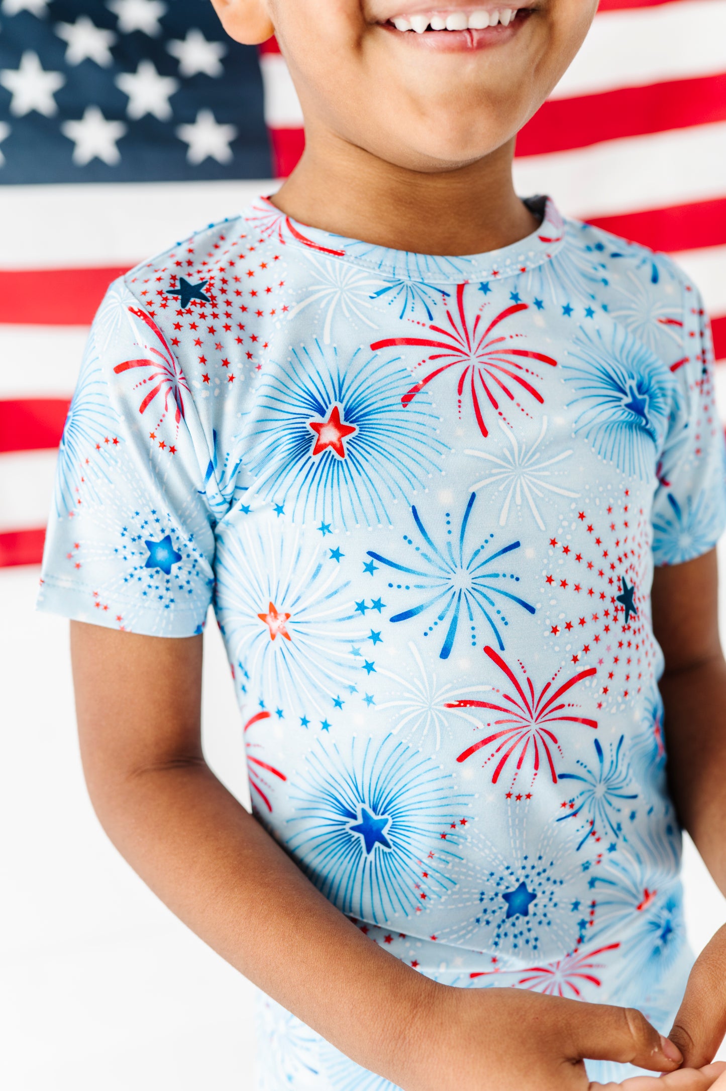 Child wearing a bamboo two-piece set with fireworks design in front of an American flag
