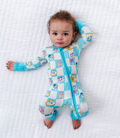 Baby wearing a colorful bamboo romper with cartoon 44 Cats characters on a white textured surface