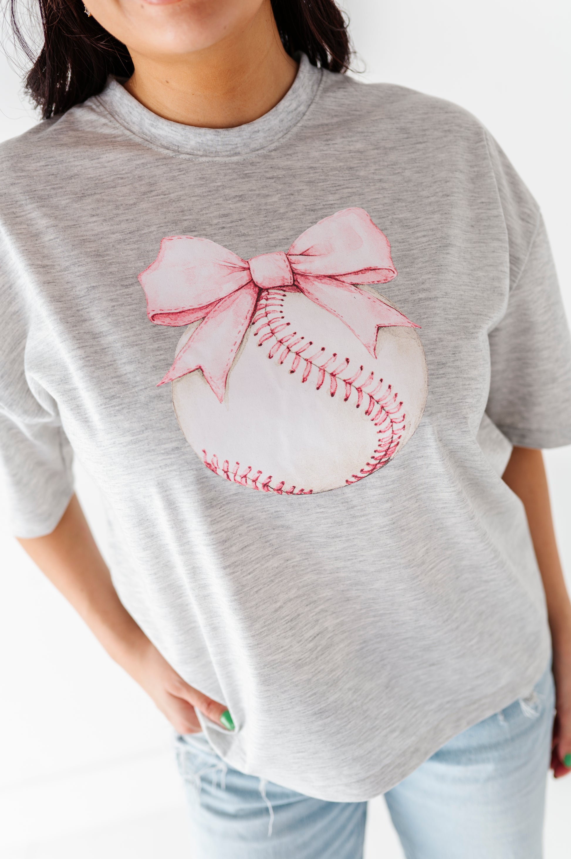 Gray t-shirt with a baseball and pink bow design worn by a Mom on a white background