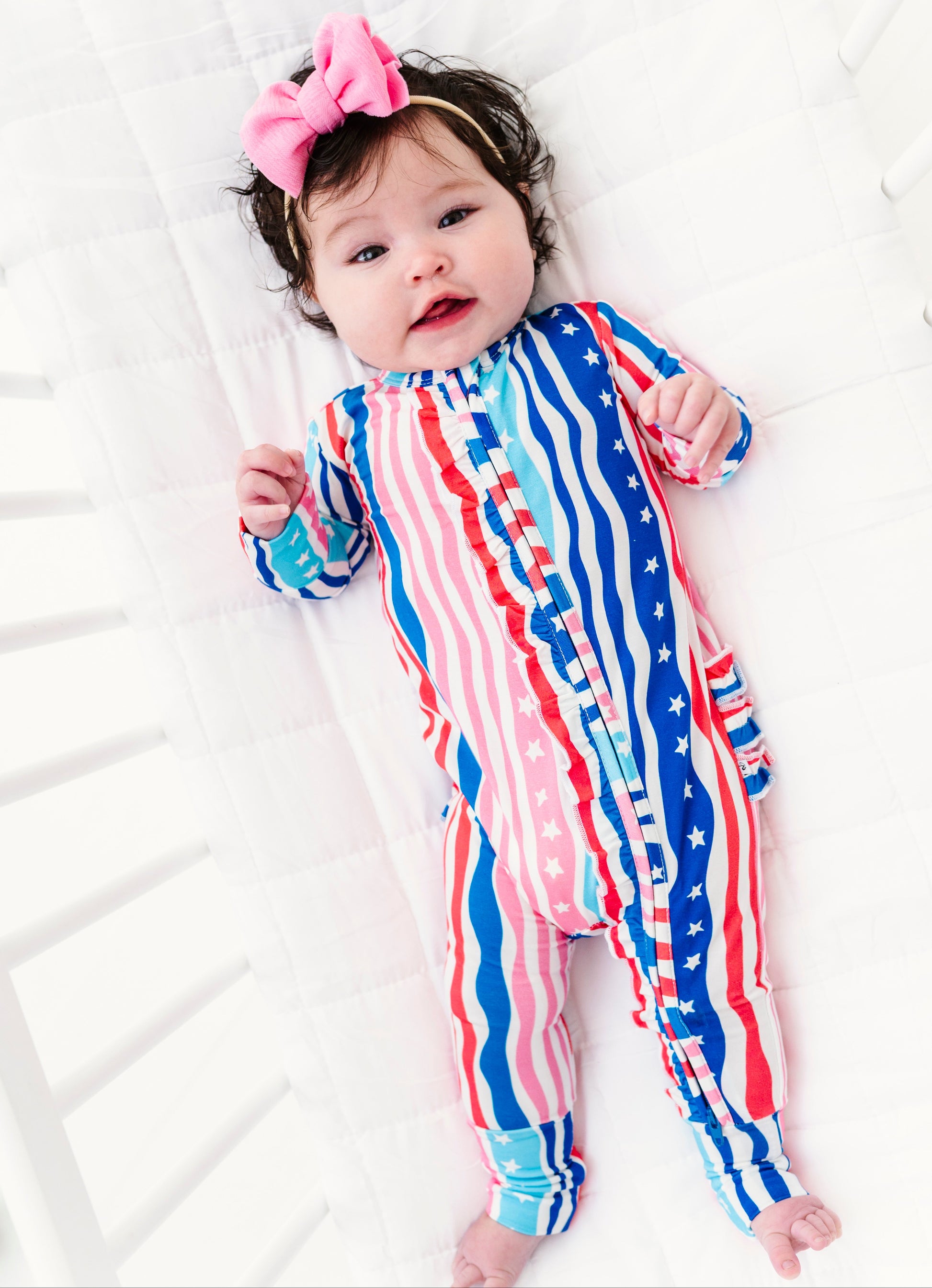 Baby wearing a red, white, and blue striped bamboo convertible romper on a white background