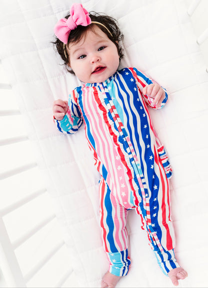 Baby wearing a red, white, and blue striped bamboo convertible romper on a white background