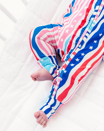 Baby's legs in American flag patterned bamboo pajamas on a white background