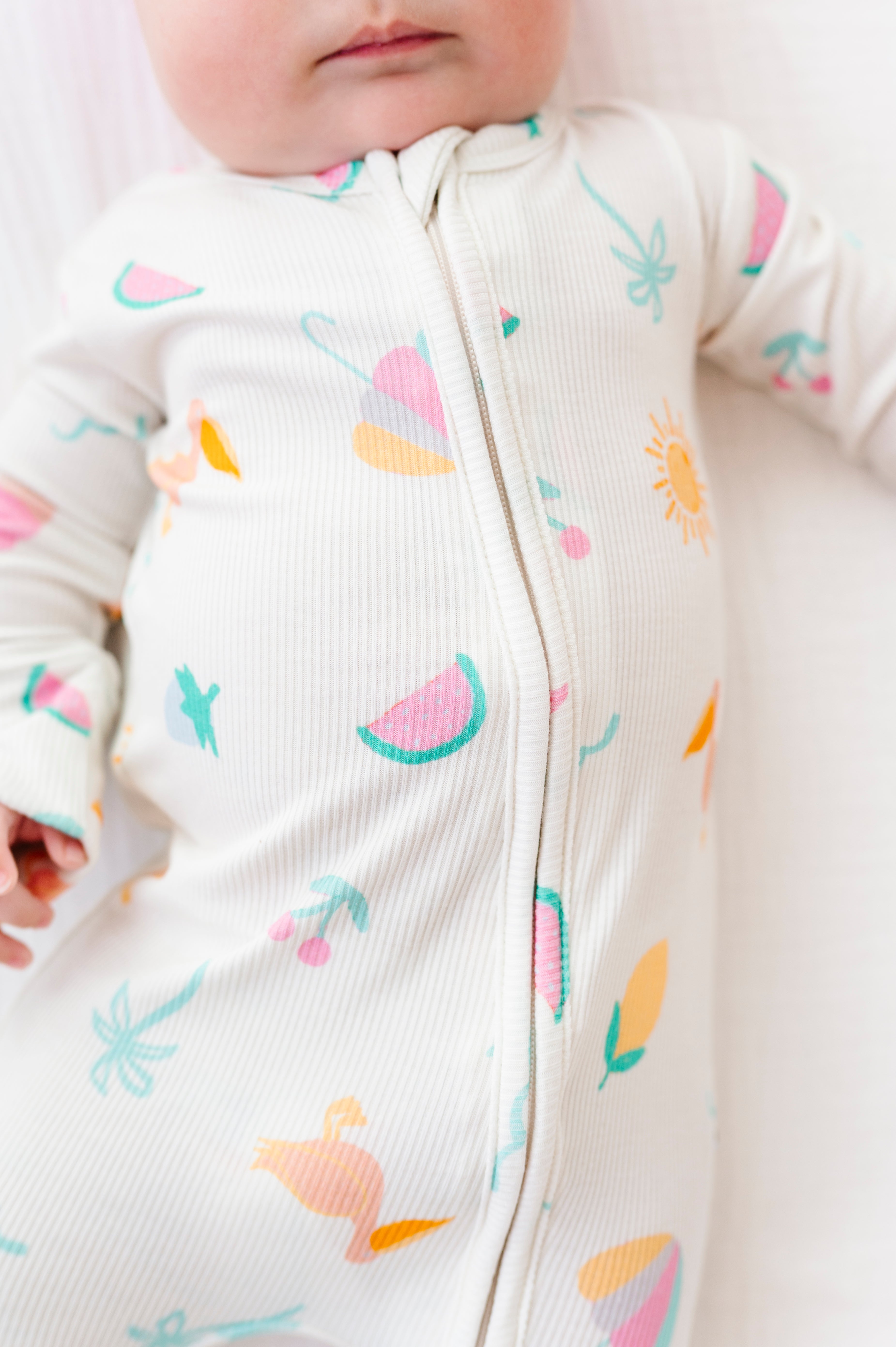Baby wearing a white onesie with colorful patterns on a white background