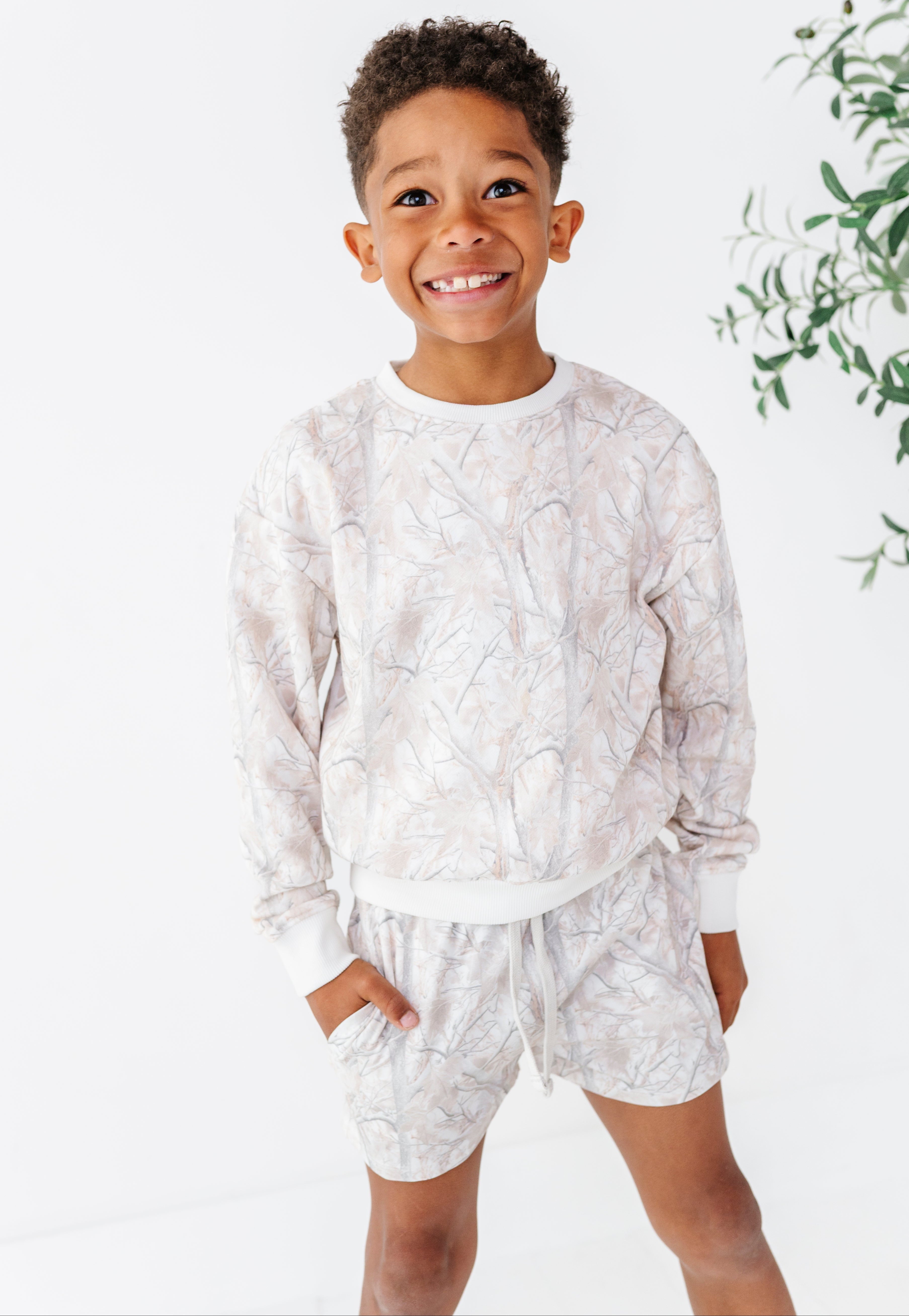 Child wearing a camo patterned outfit on a white background