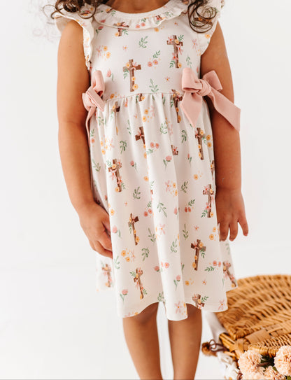 Young girl wearing a floral bamboo dress with cross patterns on a white background