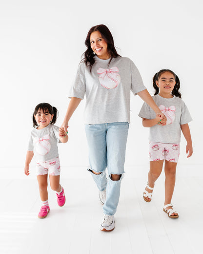 Mom and daughters wearing matching gray baseball-themed t-shirts and pink checkered bamboo biker shorts 