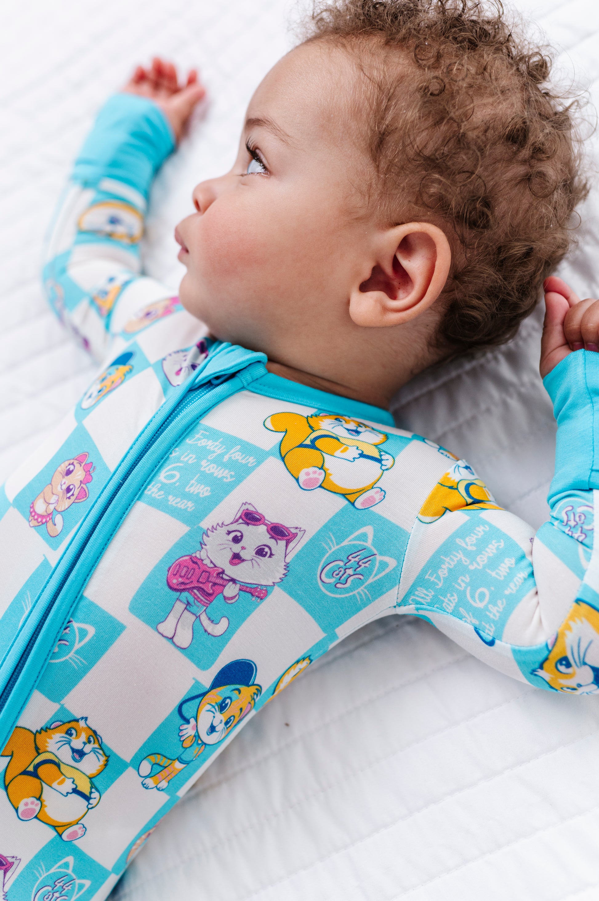 Baby wearing a colorful bamboo romper romper with cartoon 44 Cats characters on a white background
