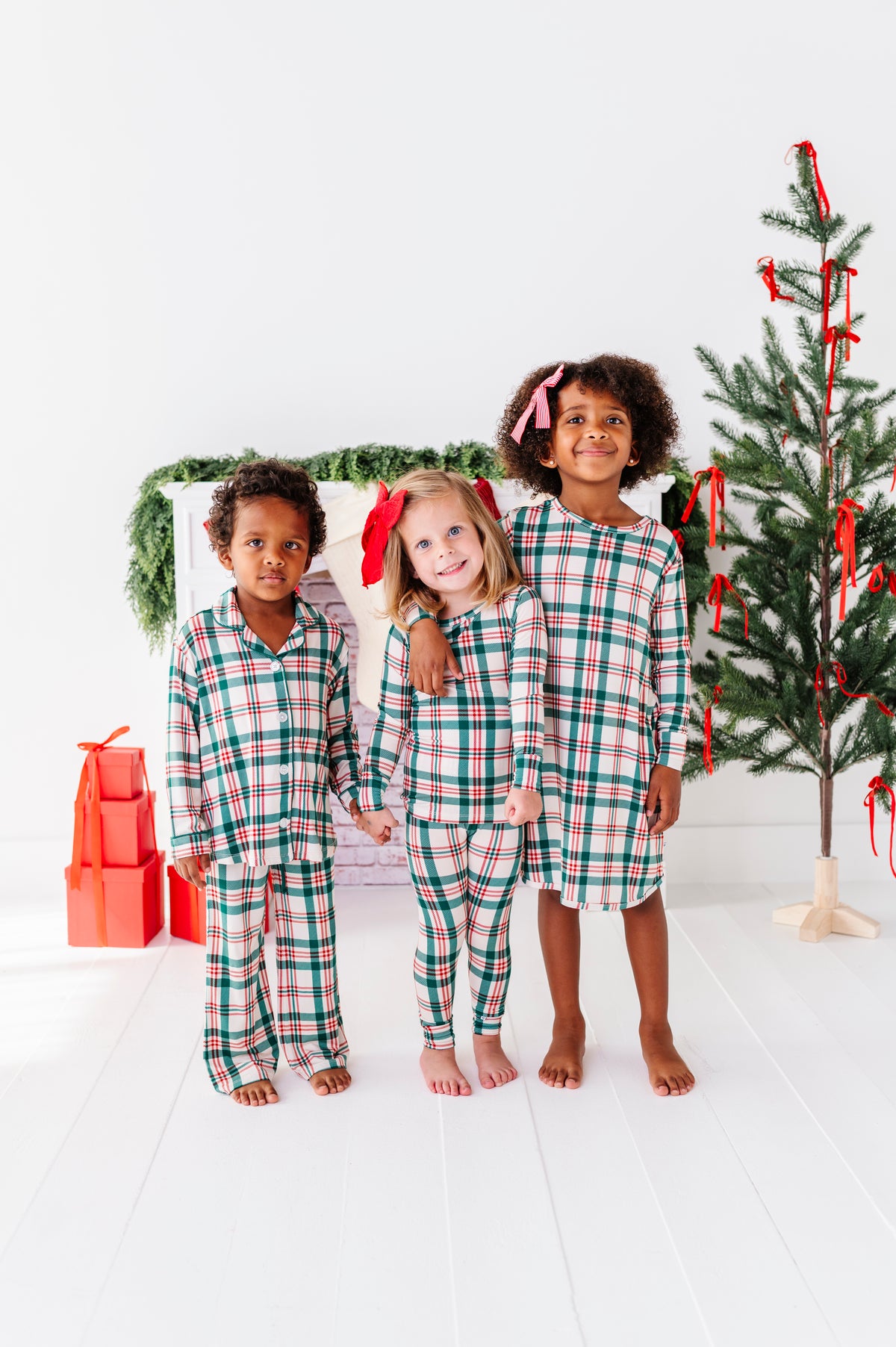 Two little girls and a boy wearing bamboo outfits in a classic Christmas plaid print 
