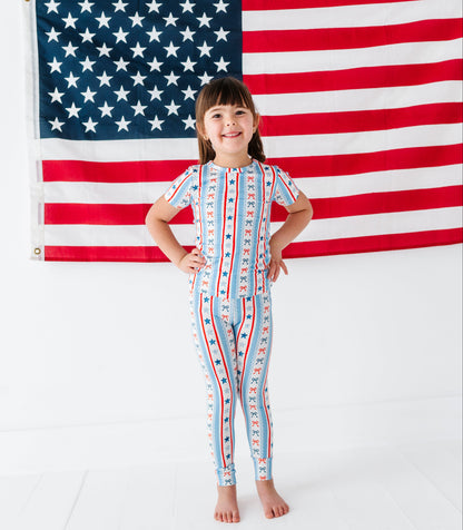 Child wearing a patriotic bamboo two-piece set pajamas in front of an American flag