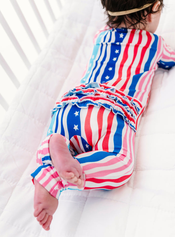 Child wearing a colorful American flag-themed romper on a white background