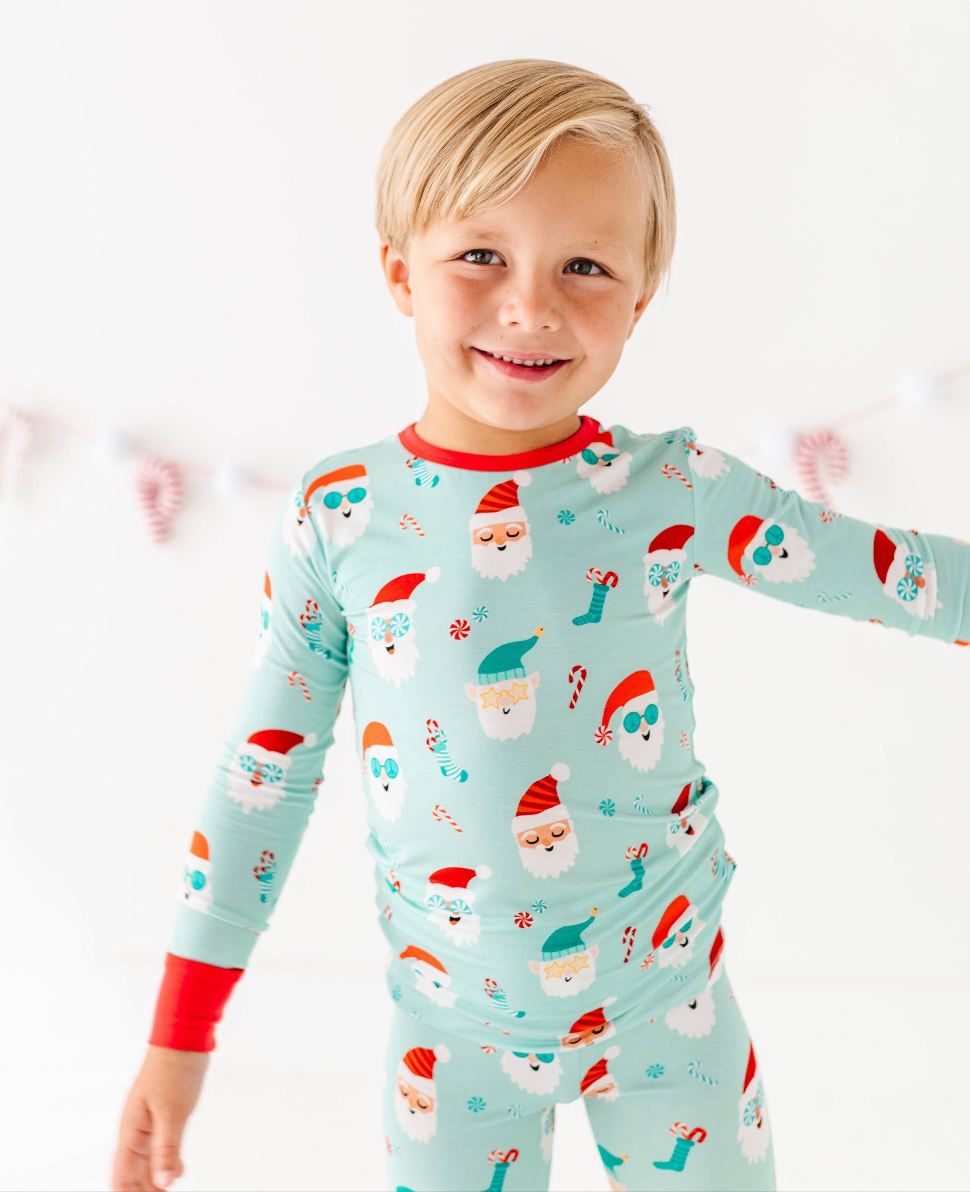 Child wearing a festive bamboo pajama set with Santa Claus design on a white background