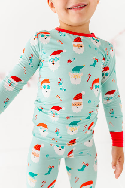 Child wearing Christmas-themed bamboo pajamas with Santa Claus and reindeer design on a light blue background.
