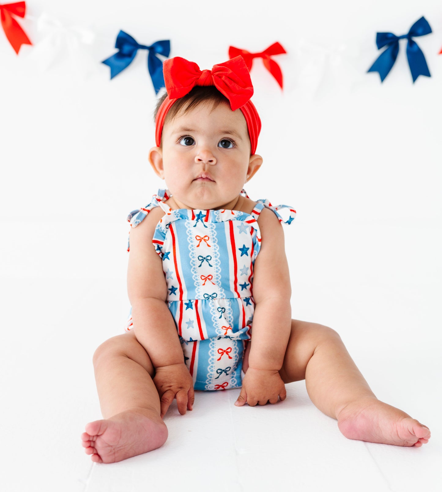 Baby wearing a bamboo patriotic outfit with red, white, and blue colors on a white background.