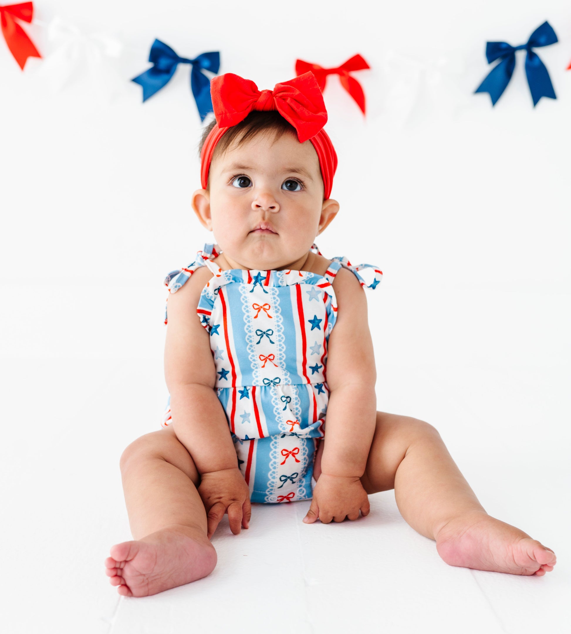 Baby wearing a bamboo patriotic outfit with red, white, and blue colors on a white background.