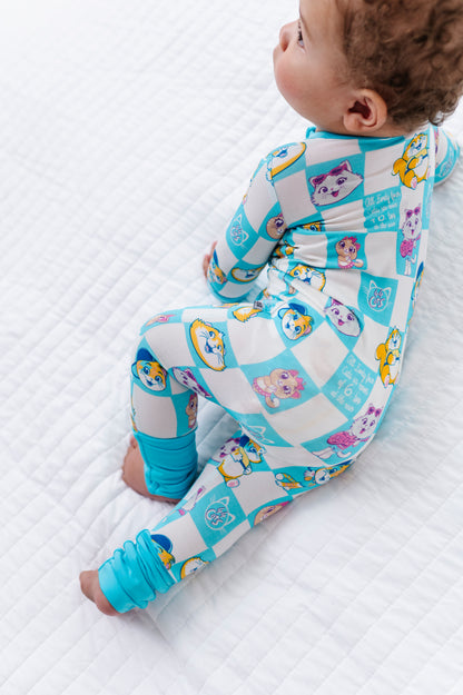 Baby in a colorful bamboo zip romper with 44 Cats characters on a white textured surface