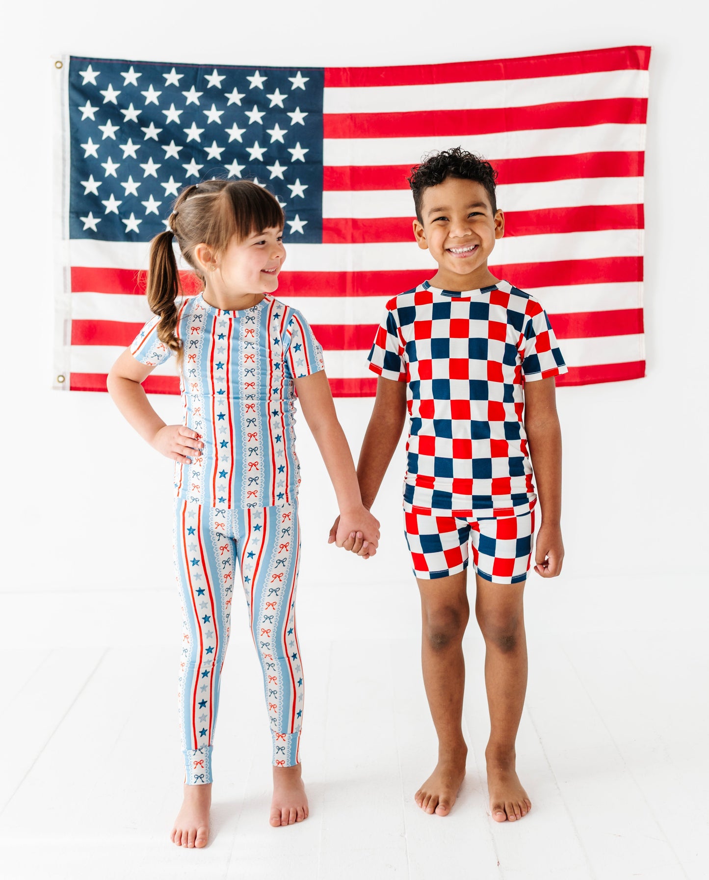 Two children wearing colorful bamboo pajamas standing in front of an American flag.