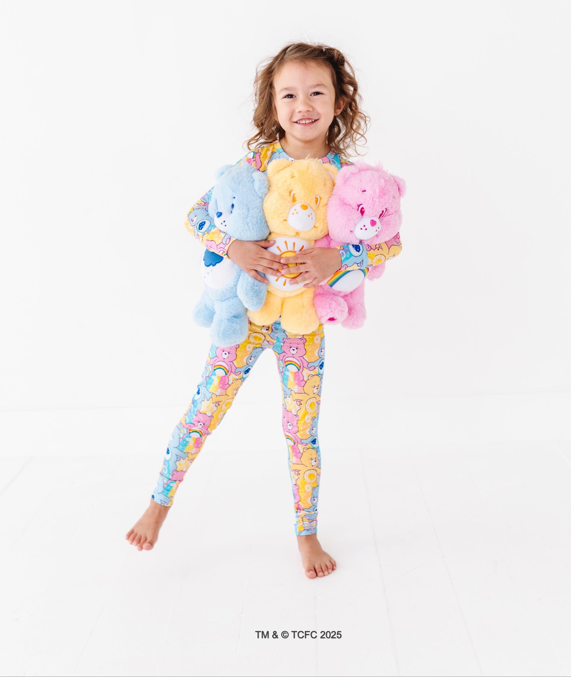 Child hugging plush Care Bears while wearing Care Bears™ Stare bamboo pajama set