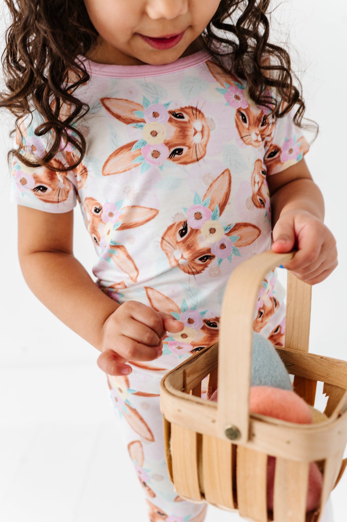 Child wearing a bamboo pajama set with bunny print, holding a wooden basket.