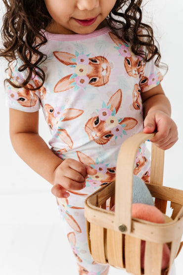 Child wearing a bamboo pajama set with bunny print, holding a wooden basket.