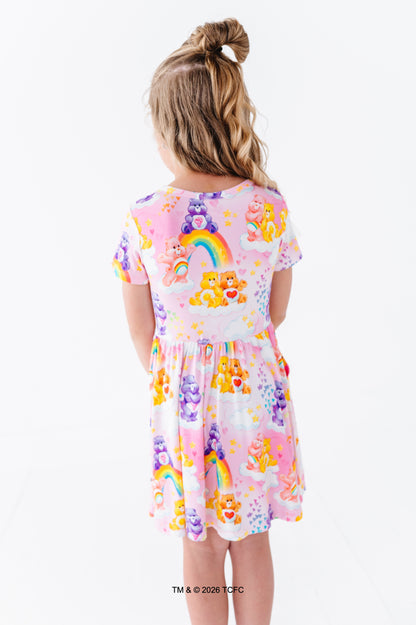 Child wearing a colorful Care Bears™ bamboo dress on a white background