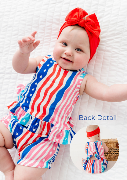 Baby wearing a colorful American flag swing top set and red headband on a white background