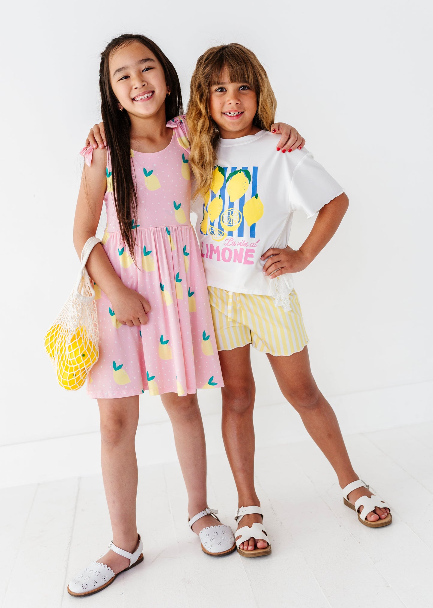 Two children wearing matching lemon themed outfits on a white background