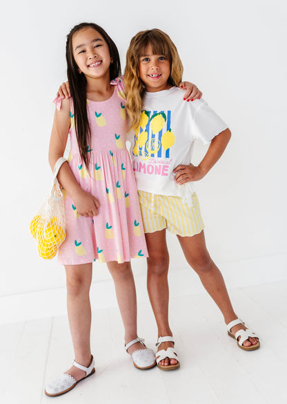 Two children wearing matching lemon themed outfits on a white background