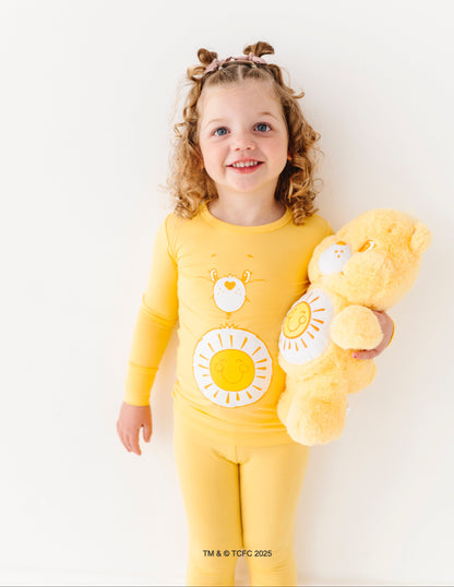 Child wearing Care Bears Funshine Bear yellow bamboo pajamas with sun belly badge